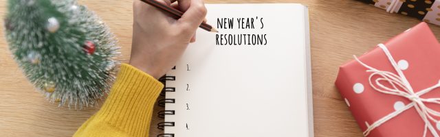 Woman hand writing New year's resolution on note paper in new ye