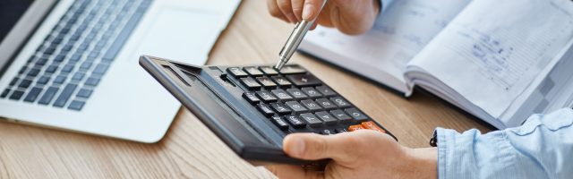 Calculando el CAC Payback Period. Plano medio de unas manos sujetando una calculadora representando el calculo del CAC Payback Period.